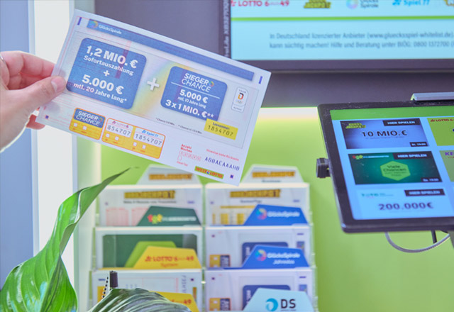 251110-GlücksSpirale-Spielschein_(c)SchlagUndRoyGmbH_640 Hand hält GlücksSpirale-Spielschein in WestLotto-Annahmestelle hoch