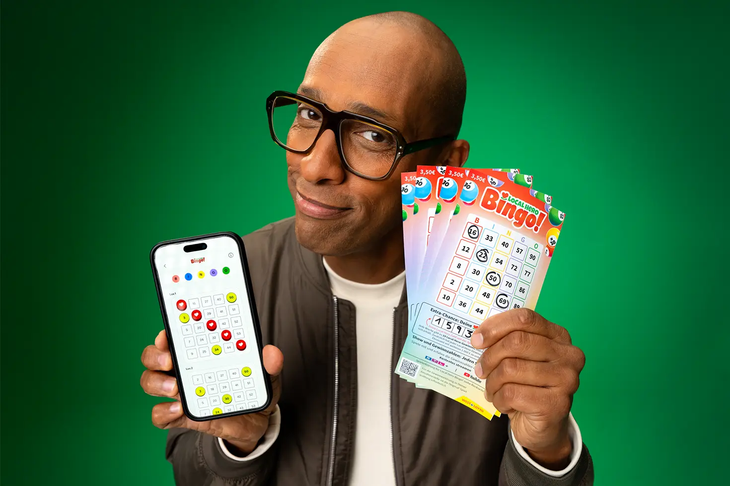 Amiaz Habtu hält ein Smartphone mit geöffneter WestLotto-App sowie mehrere Local Hero Bingo!-Lose in die Kamera.