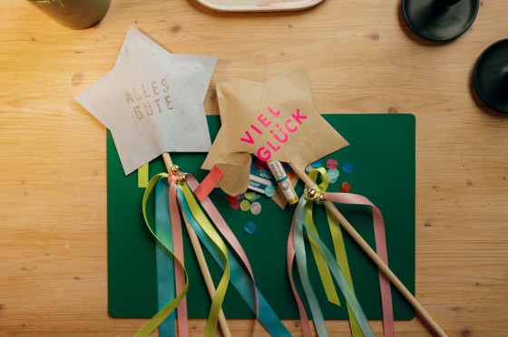 Zwei gebastelte Sterne mit Satinbändern und kleinen Glöckchen an einem Holzstock - WestLotto DIY-Idee GlücksSpirale