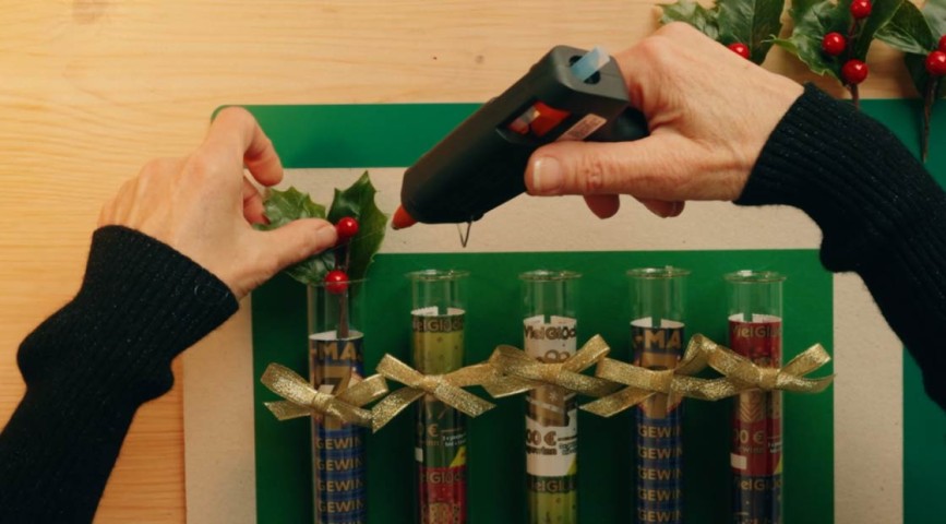 Rubbellos-DIY: Mit WestLotto-Rubbellosen befüllte Glasröhrchen werden mit Stechpalmenzweigen verziert 