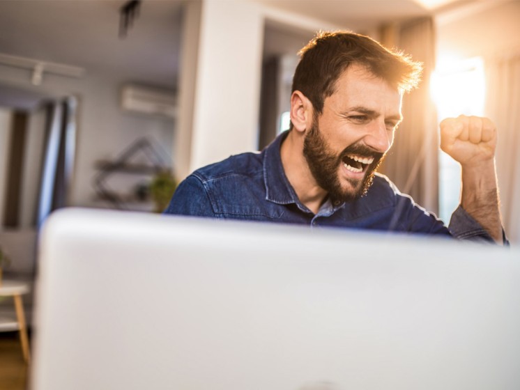 Mann sitzt vor Laptop und jubelt | WestLotto Eurojackpot-Gewinner
