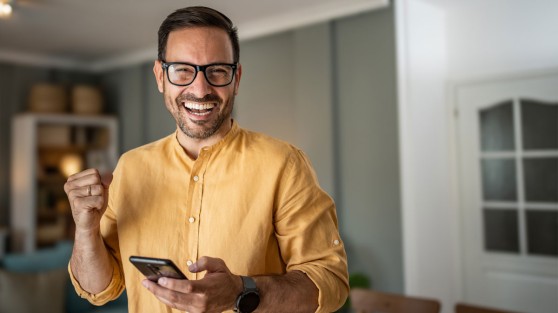 Mann hält Handy in der Hand und jubelt | Eurojackpot-Gewinner NRW