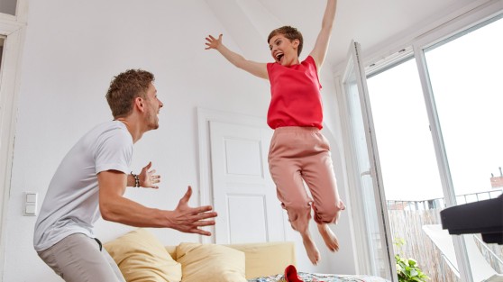 Ein Mann und eine Frau jubeln in einer Wohnung. WestLotto-Gewinnerbilanz
