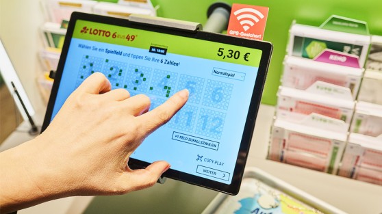 Eine Hand tippt LOTTO-Zahlen auf einem Tablet-Terminal von WestLotto