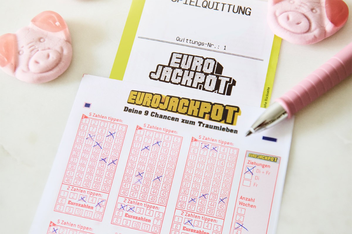 Ein Eurojackpot-Spielschein und eine -Spielquittung liegen auf einer weißen Unterlage - WestLotto NRW-Gewinner