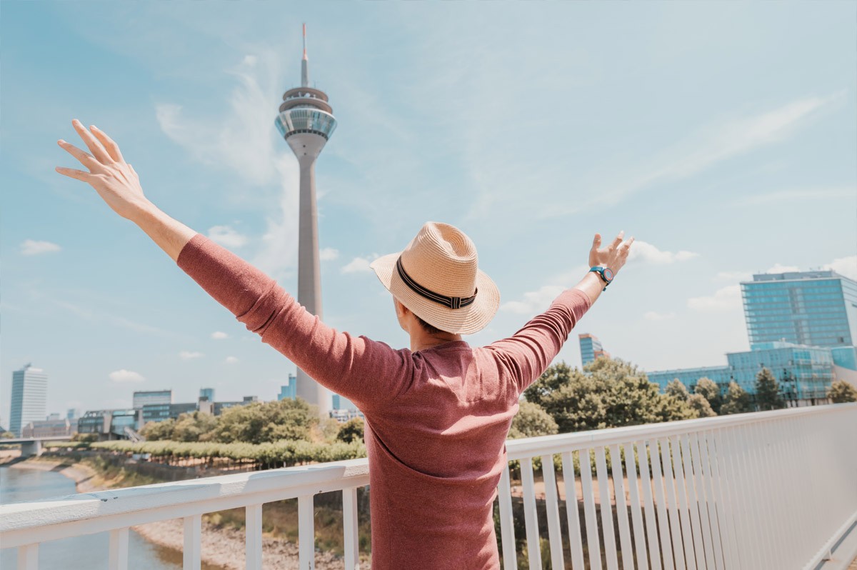 Mann steht vor Düsseldorfer Fernsehturm und freut sich. WestLotto