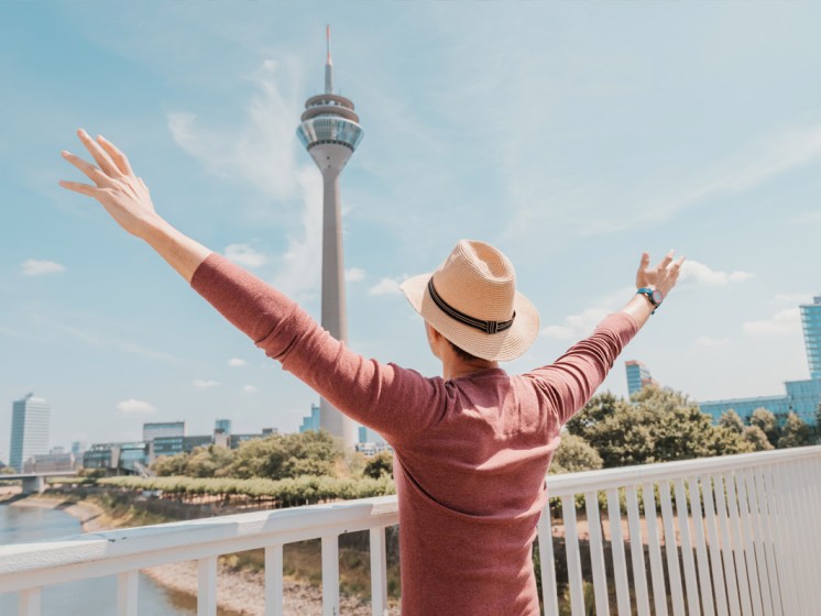 Mann steht vor Düsseldorfer Fernsehturm und freut sich. WestLotto