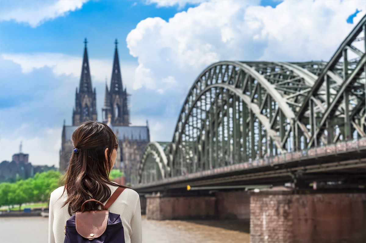 Frau von hinten, die am Rhein steht und auf Kölner Dom blickt - WestLotto Eurojackpot-Gewinner