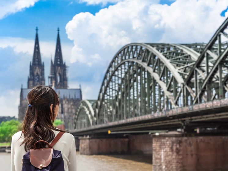 Frau von hinten, die am Rhein steht und auf Kölner Dom blickt - WestLotto Eurojackpot-Gewinner