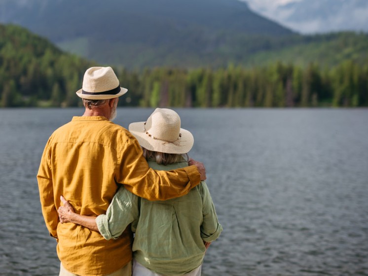 Paar von hinten, welches vor einem See mit Bergkulisse steht - WestLotto Gewinner Rubbellos
