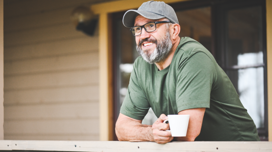 Mann sitzt auf Sessel, schaut auf Handy und freut sich | Gewinner WestLotto-Rubbellos