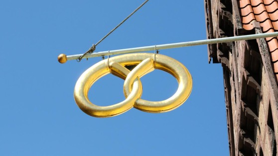 Goldene Brezel, die an einem Haus hängt | WestLotto Glücksbringer LOTTO 6aus49