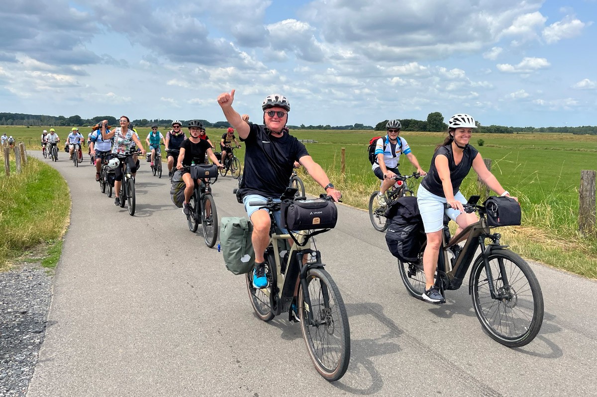 Mehrere Fahrradfahrer fahren auf einem Weg zwischen zwei Feldern | NRW-Radtour