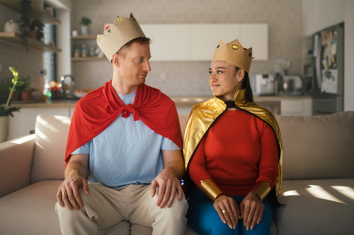 Ein Mann und eine Frau sitzen mit einer Pappkrone auf dem Kopf auf dem Sofa | WestLotto-Rubbellos Krone