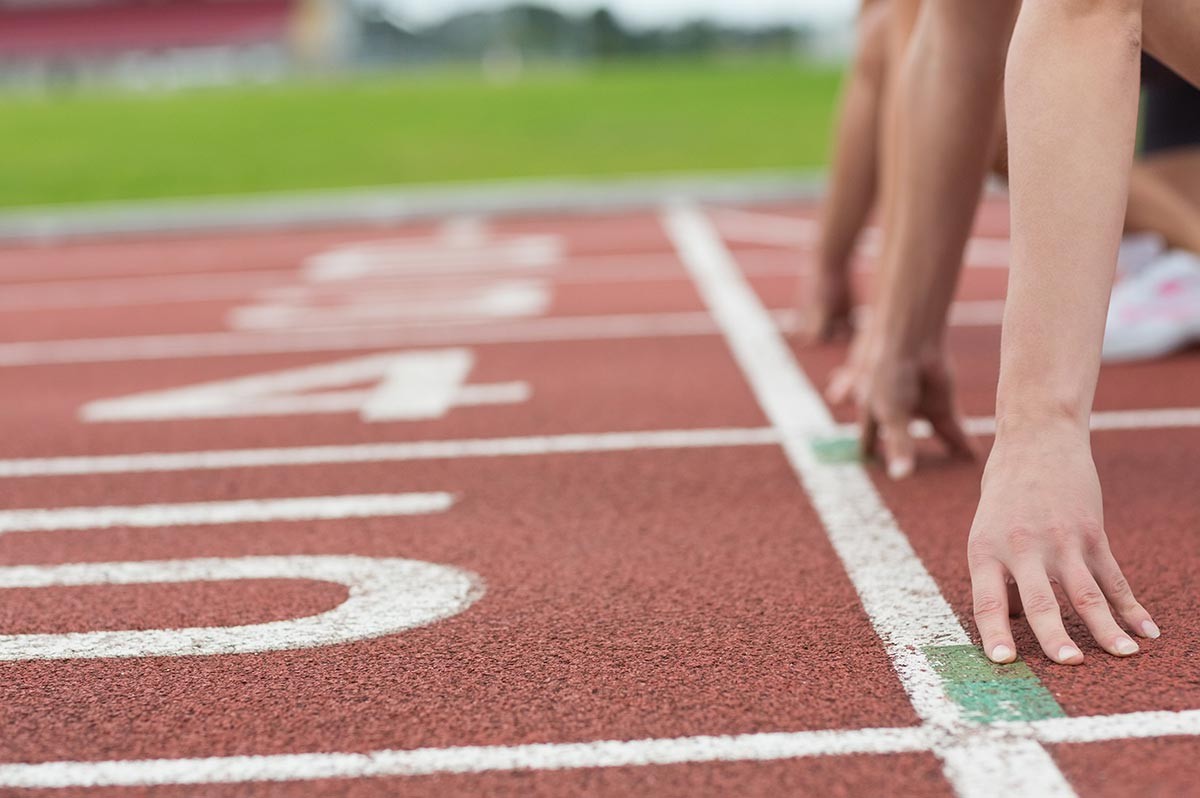 Athleten in Startposition auf einer Leichtathletik-Laufbahn