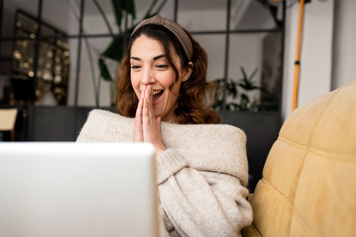 Frau hält gefaltete Hände vor den Mund und schaut freudig auf Laptop | WestLotto LOTTO 6aus 49 Millionäre