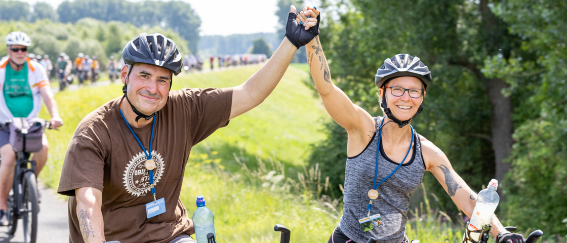 Zwei Radfahrer grüßen zusammen in die Kamera | WestLotto NRW-Radtour