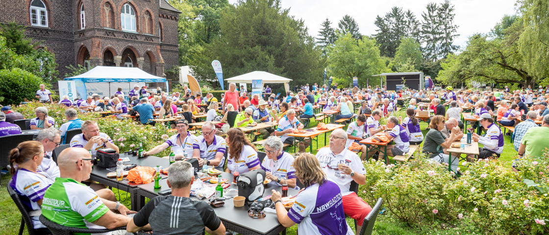 Viele Menschen machen Pause in einem Schlossgarten | WestLotto NRW-Radtour 