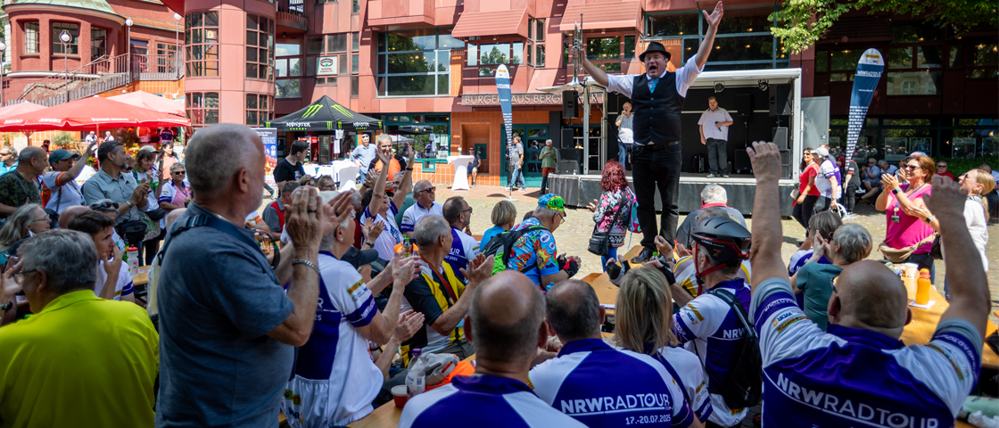Viele Menschen singen zusammen an Bierzelt-Tischen | WestLotto NRW-Radtour