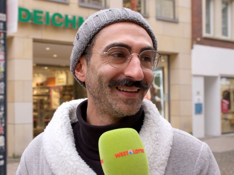 Mann mit Brille und Mütze wird interviewt | WestLotto Straßenumfrage