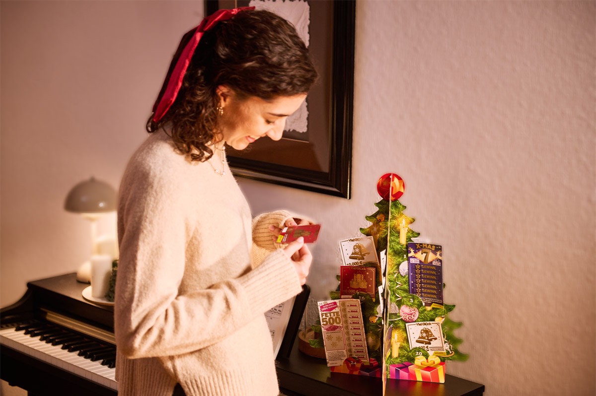 Frau steht vor Klavier, auf dem Rubbellos-Adventskalender von WestLotto steht