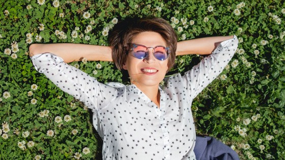 Frau mit Sonnenbrille liegt auf einer Wiese | WestLotto