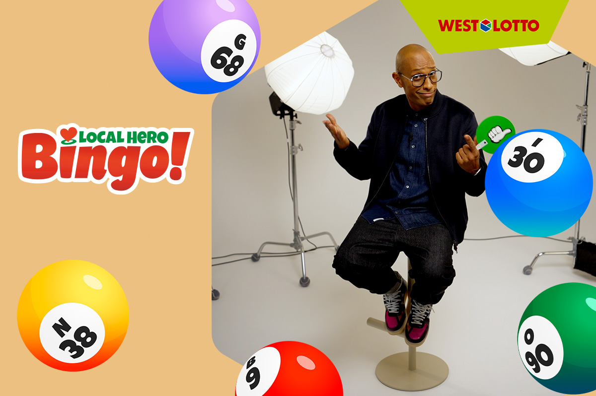 Amiaz - Moderator der Local Hero Bingo-Show - sitzt in einem Studio auf einem Barhocker. Daneben Bingo!-Kugeln. WestLotto