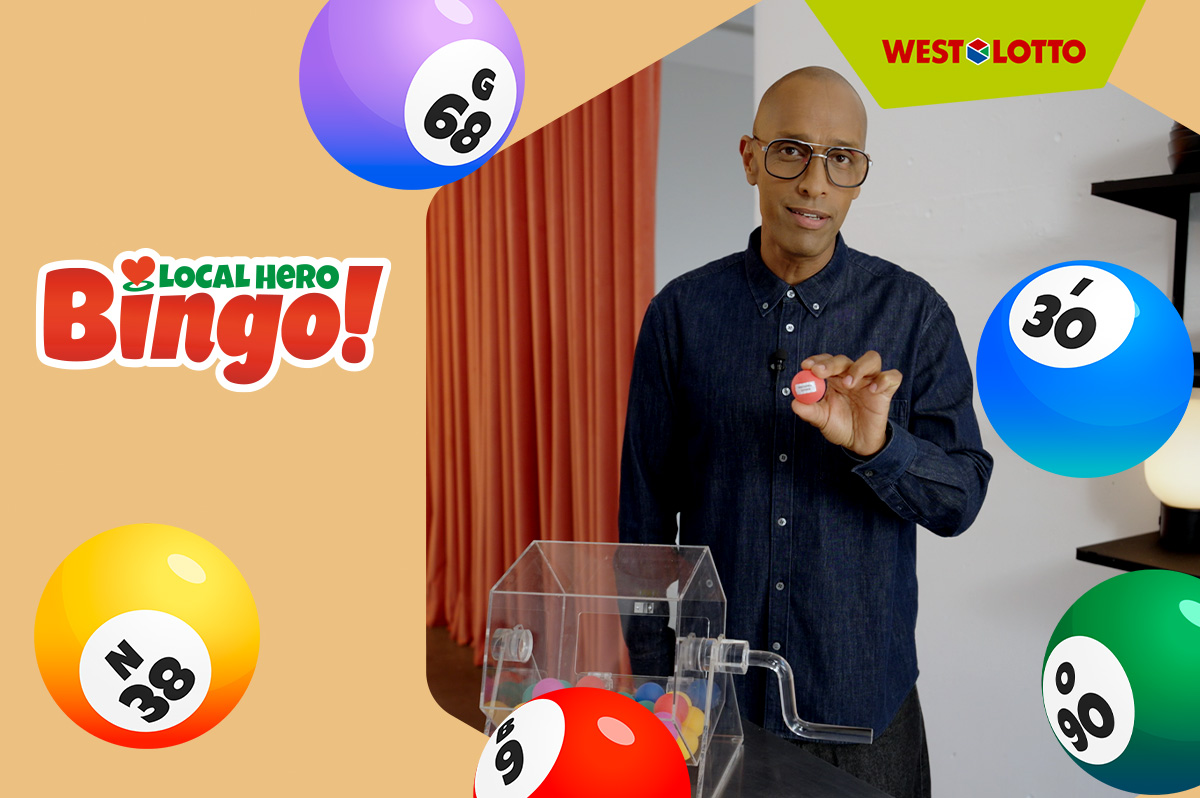 Amiaz - Moderator von Local Hero Bingo! - steht in einer Loft-Küche vor einer Bingo-Trommel.