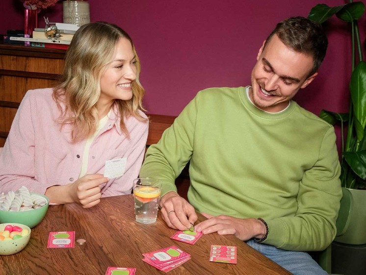 Pärchen sitzt an Esstisch, spielt Rubbelquiz Lucky Bunch und freut sich - WestLotto