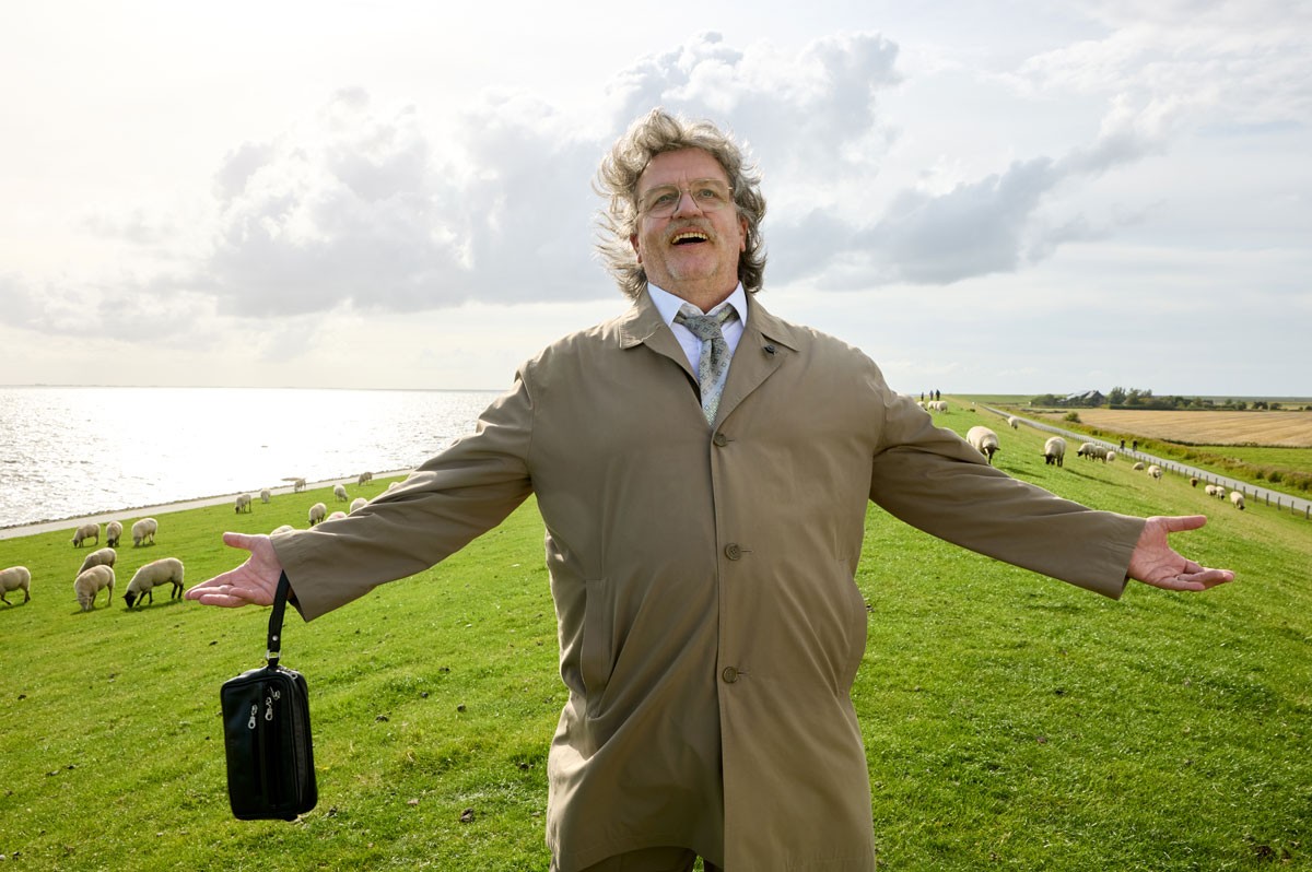 Horst Schlämmer steht auf Wiese und reißt die Arme glücklich auseinander