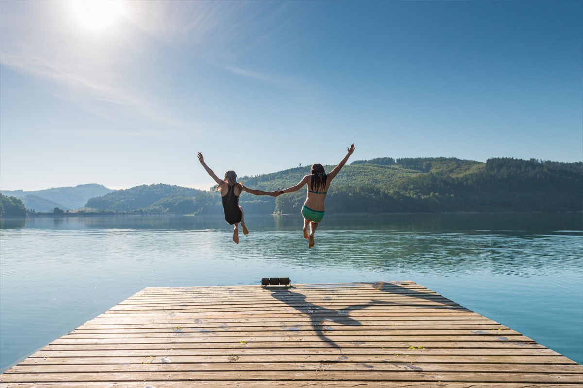 Zwei Personen springen von einem Steg aus in einen See | WestLotto-Ausflugstipps NRW