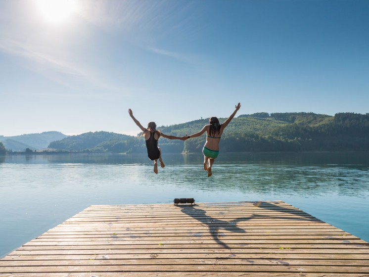 Zwei Personen springen von einem Steg aus in einen See | WestLotto-Ausflugstipps NRW