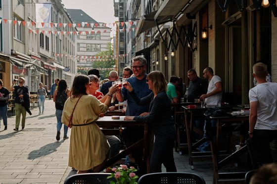 Eine kleine Gruppe trinkt in der Düsseldorfer Altstadt außerhalb einer Kneipe Bier 