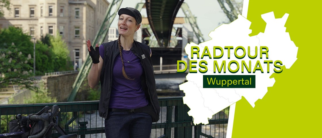 Radfahrerin steht vor Schwebebahn in Wuppertal. Daneben Schriftzug Radtour des Monats - Wuppertal | WestLotto