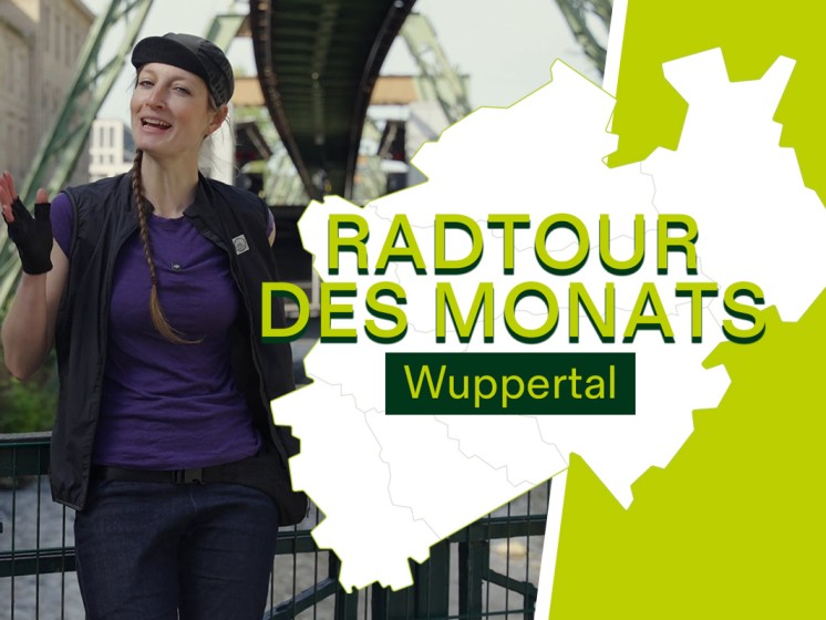 Radfahrerin steht vor Schwebebahn in Wuppertal. Daneben Schriftzug Radtour des Monats - Wuppertal | WestLotto