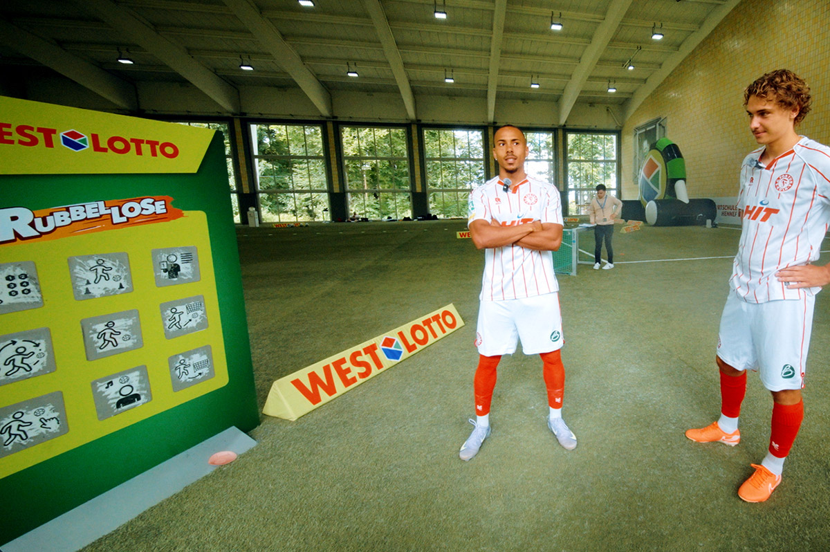 Zwei Spieler der Regionalliga West stehen vor überdimensionalem WestLotto-Rubbellos