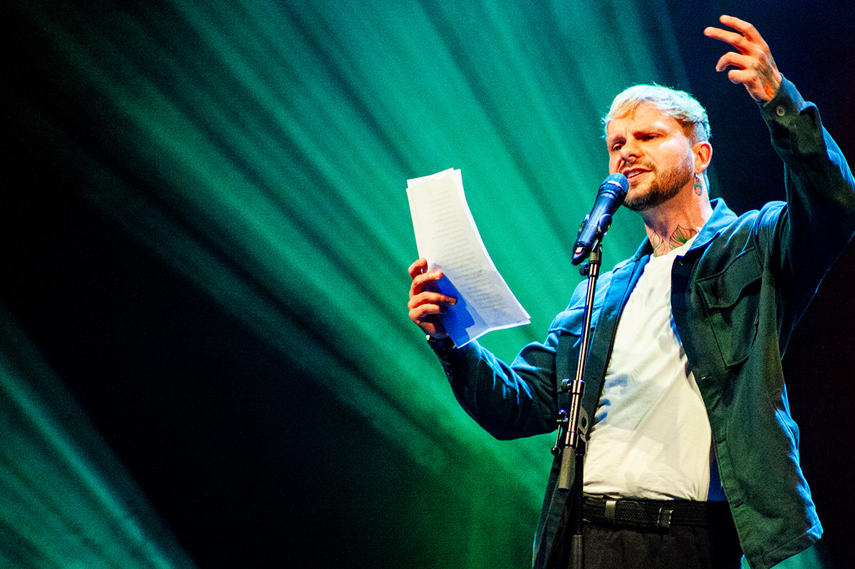 Poetry-Slammer hält Zettel in der Hand und spricht in Mikrofon - WestLotto