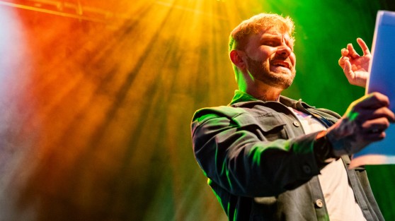 Poetry-Slammer hält Zettel in der Hand und spricht in Mikrofon - WestLotto