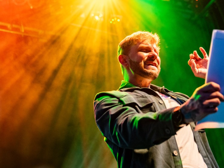 Poetry-Slammer hält Zettel in der Hand und spricht in Mikrofon - WestLotto